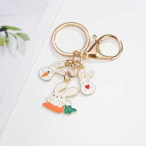 Detail view of golden lobster clasp with three cute cartoon bunny pendants on a key ring