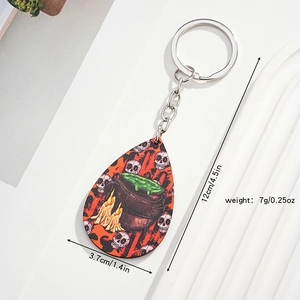 Detail of Halloween keychain showing skull, green cauldron, and candle patterns on teardrop pendant