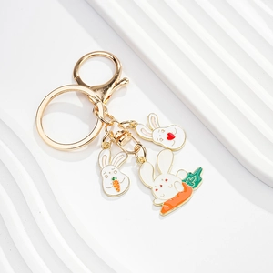 Detail of three white enamel bunny charms on a gold keychain with carrot motifs