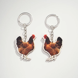 Close-up of dual realistic brown hen keychains with silver metal rings on white background