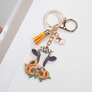 Detailed view of custom cow keychain with sunflower pattern, tassel, and name tag detail