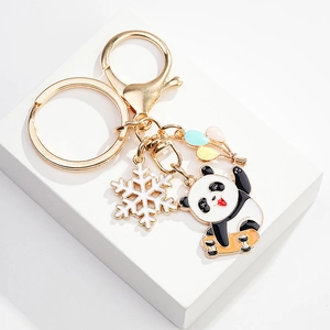 Detailed close-up of a gold metal keychain with a cute panda on a skateboard and snowflake