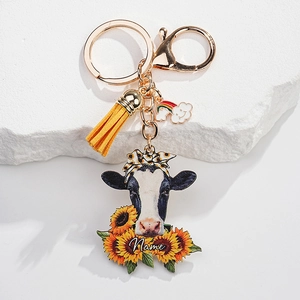 Detailed view of a personalized cow keychain with yellow tassel and sunflower motif