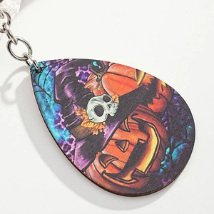 Macro view of teardrop wooden earring featuring festive pumpkin and skull patterns