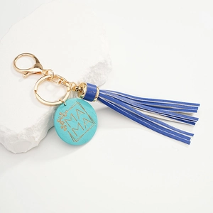 Blue leather tassel keychain with turquoise MAMA charm on white stone decorative background