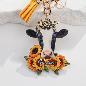 Detail of sunflower cow keychain with yellow tassel and rainbow charm on stone base
