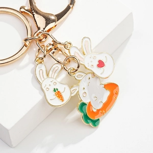 Detail of cute golden enamel bunny charms featuring carrot and heart on a metal keychain