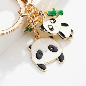 Detail of cute panda metal keychain with golden ring and green bamboo leaf pendant