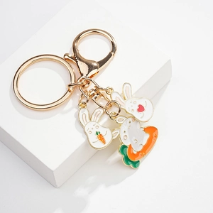 Detail of golden metal keychain with cute enamel rabbit charms and a carrot pendant