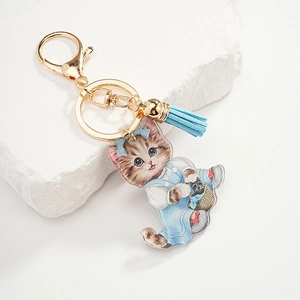 Cute cartoon cat acrylic keychain with blue tassel and gold hardware on white stone