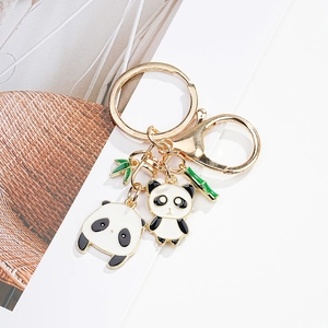 Detail of cute enamel panda charms and green bamboo leaves on a gold keychain