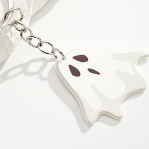 Macro shot of a white Halloween ghost keychain with deep red eyes and silver metal hook