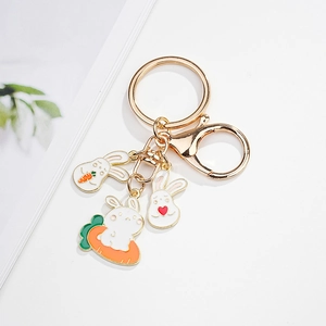 Detailed close-up of golden keychain featuring three cute cartoon bunny pendants with carrots