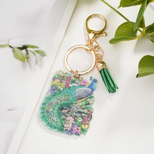 Artistic peacock painted acrylic keychain with green tassel on a clean white background