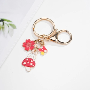 Detail of cute rabbit keychain with cherry blossom and mushroom charms in gold metal