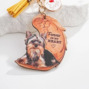 Detail of Yorkshire Terrier keychain with yellow tassel on white stone background