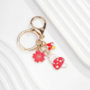 Detail of cute rabbit keychain with cherry blossom and mushroom charms in golden finish