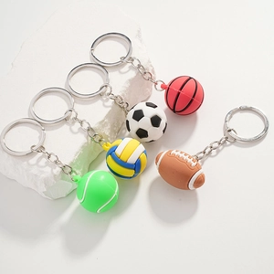 Five assorted sports ball keychains including tennis soccer and basketball on white stones