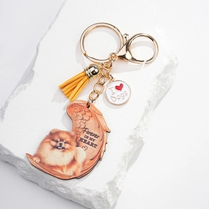 Detail of Pomeranian dog memorial keychain with yellow tassel on white stone