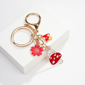 Detail of cute rabbit and red mushroom pendants on a polished gold-tone metal keychain