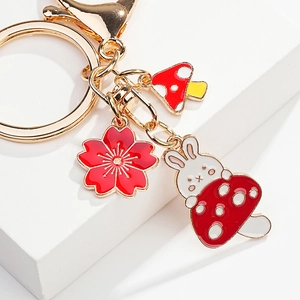 Detail of golden rabbit keychain featuring enamel cherry blossoms and mushroom charms