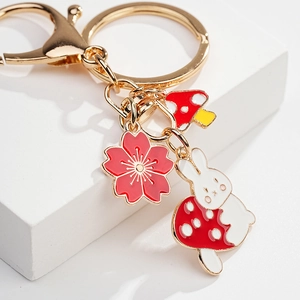 Detailed close-up of a golden alloy keychain with cute rabbit and red mushroom charms