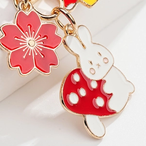 Detail showing a white rabbit on a red mushroom charm and a cherry blossom pendant