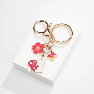 Detail view of gold keychain with colorful enamel charms featuring rabbit, flower and mushroom