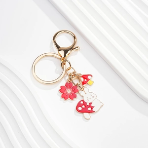 Detail of cute rabbit and mushroom charms on a gold keychain with lobster clasp