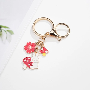 Detail of a golden metal keychain with cute enamel rabbit, mushroom, and sakura charms