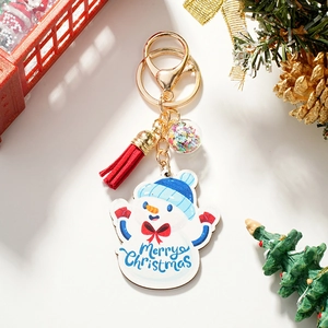Close-up of wooden snowman keychain with blue Merry Christmas print and red tassel