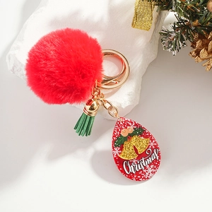 Détail d'un porte-clés pompon rouge avec gland vert et breloque de Noël en acrylique
