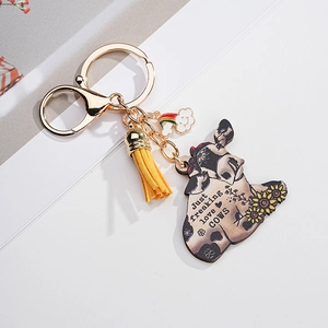 Detail of sunflower cow keychain with yellow tassel and golden metal clasp on white background