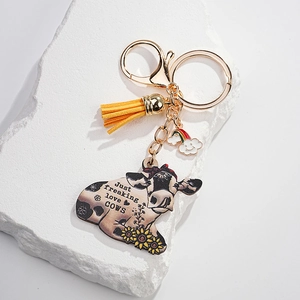 Detail of sunflower cow keychain with gold hardware, yellow tassel and rainbow cloud charm