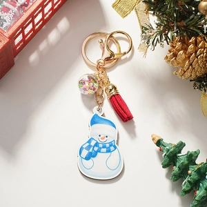 Detail of wooden snowman keychain with golden ring, red tassel, and sparkling sequin ball