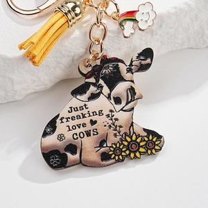 Detail of cow keychain with Just freaking love COWS text, yellow tassel and sunflower detail