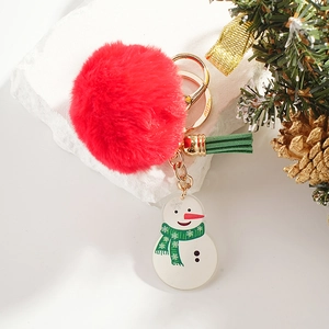 Christmas snowman keychain with red pom-pom and green tassel on a white stone background