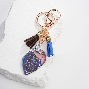 Detail of sloth metal keychain featuring a heart pendant with quotes and suede tassels