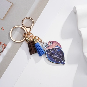 Detail of sloth acrylic heart keychain with gold ring and dual blue-brown suede tassels