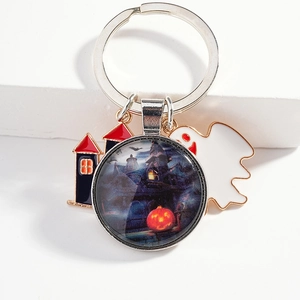Halloween keychain with ghost, castle, and pumpkin pendants on a white stone background