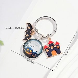 Macro shot of Halloween keychain with black bat, pumpkin glass dome and metal castle charms