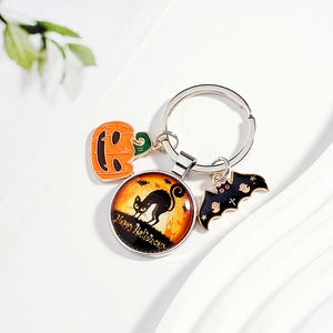 Halloween keychain with pumpkin, bat and glass cat pendant on white wave background