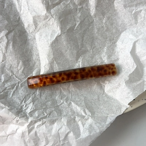 Detailed view of a vintage tortoiseshell barrette on white textured art paper background