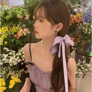 Détail de pince à cheveux nœud en soie lavande avec boucles cerises et collier de perles