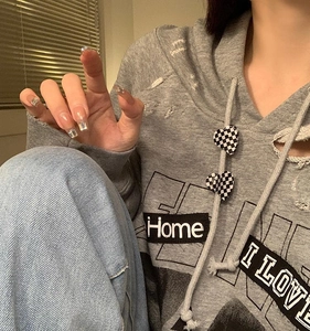 Close-up of gray hoodie featuring distressed holes and heart checkerboard drawstring charms