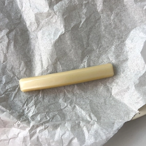 Close-up of a minimalist cream resin hair clip showing its smooth and glossy finish