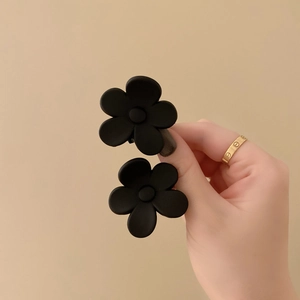 Detailopname van kleine zwarte matte acryl bloem haarklemmen met minimalistisch ontwerp