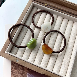 Détail de trois élastiques à cheveux avec breloques en résine en forme de cœur en bois