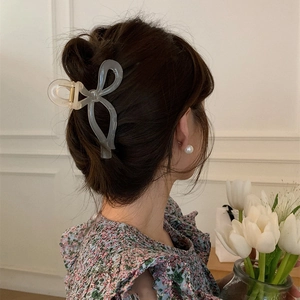 Translucent grey bow hair claw clip styled on a low bun hair arrangement for women