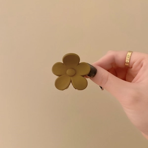 Detailopname van de mat olijfgroene bloem haarklem met een minimalistisch bloemontwerp